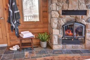 Ein Steinkamin in einer Blockhütte mit einem Tisch und einem Fenster in der Unterkunft Chic Familiale, Relaxant avec spa en montagnes in Labelle