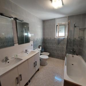 ein Badezimmer mit zwei Waschbecken, einer Toilette und einer Badewanne in der Unterkunft Villa Naomi in Les tres Cales + 5 Fotos