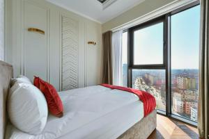 シュチェチンにあるMARGI Dali Apartament PRESTIGE LUX HANZA TOWERのベッドルーム1室(赤い枕のベッド1台、大きな窓付)