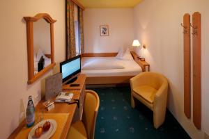 a hotel room with a bed and a desk with a computer at Hotel Am Reschensee in Resia