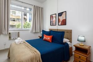 a bedroom with a blue bed and a window at Quarto&Sala Completo a 300m da Praia | NSC 386/402 in Rio de Janeiro