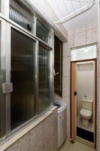 a bathroom with a toilet and a glass shower door at Quarto&Sala Completo a 300m da Praia | NSC 386/402 in Rio de Janeiro