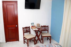 a small table with two chairs and a television on a wall at Hotel Los Jardines in Santiago de los Caballeros