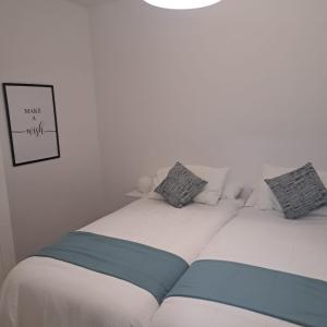 1 dormitorio con 2 camas de color blanco y azul en Apartamento Neron, en Ronda