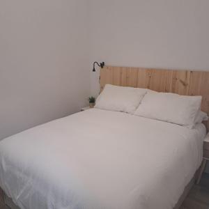 a white bed with a wooden headboard and white sheets at Apartamento Neron in Ronda