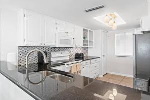 a kitchen with white cabinets and a black counter top at Commodore 410 in Panama City Beach