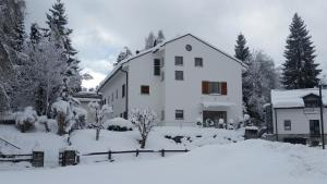 ein großes weißes Haus mit Schnee auf dem Boden in der Unterkunft Casa Alva in Flims