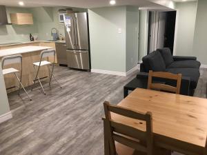 a living room with a couch and a table and a kitchen at Upscale 2-Bedroom Basement Apartment in London