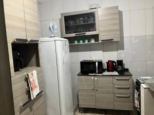 eine kleine Küche mit Kühlschrank und Mikrowelle in der Unterkunft Casa de praia in Caraguatatuba