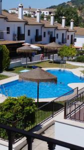 Una piscina con sombrilla y algunos edificios. en La Bondadosa, en El Bosque