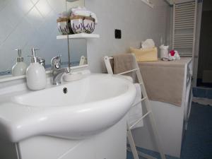 een badkamer met een witte wastafel en een plank met handdoeken bij B&B Corte dell' Idume in Lecce