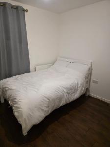 a bed with white sheets and a gray curtain at Glory Home 1 in Dartford