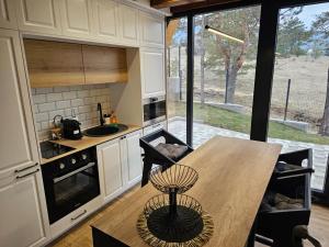 a kitchen with a wooden table and a counter top at Planinska kuća Homey in Zlatibor