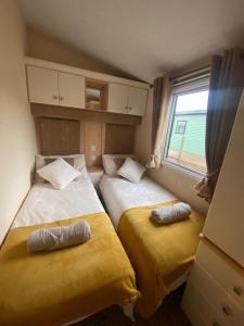 two beds in a small room with a window at Skiddaw Lodges- The Lake District in Plumbland