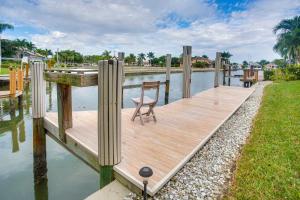 Un muelle de madera con una silla en el agua. en Upscale Marco Island Villa with Outdoor Bar and Pool!, en Marco Island