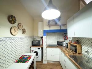 a kitchen with white cabinets and a stove top oven at Oliva Guesthouse in Vila Franca de Xira