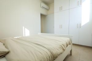 a white bedroom with a large bed with white cabinets at Lito - Slow Living in Larnaka