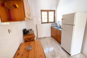 a kitchen with a white refrigerator and a wooden table at Kanali seaside apartment Poros 1 in Poros