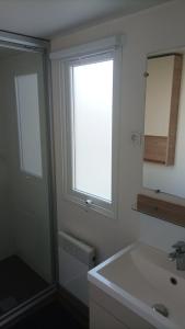 a bathroom with a sink and a window and a mirror at MH 475 ELEGANZIA 2CH ET 1sdb dans camping 4 étoiles avec parc aquatique in Saint-Julien-en-Born