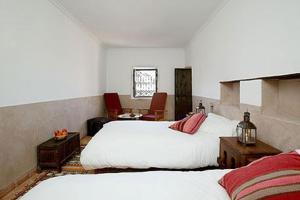 a bedroom with two beds and a table and chairs at Dar Sihamou in Tabant