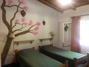 a bedroom with two beds and a tree on the wall at La Casa de Wanda in Villa de Las Rosas