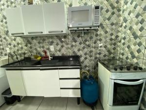 a small kitchen with a sink and a microwave at Casa Aconchego 1 Residencial Santa Terezinha in Dourados +3 photos