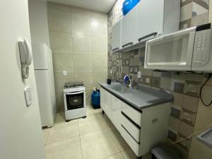 a small kitchen with a sink and a microwave at Casa Aconchego 2 Residencial Santa Terezinha in Dourados