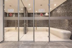 a glass door in a bathroom with a tub at Pirin Sense Gorgeous Ap SPA - FREE Parking in Bansko