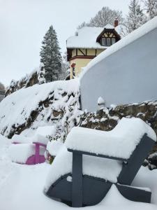 a bench covered in snow in front of a house at Ferienwohnungen im Kreuztal in Neuwerk