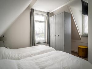 a white bedroom with two beds and a window at Bungalow in Central De Cocksdorp in De Cocksdorp