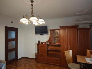 a room with a cabinet and a television and a chandelier at Dom Lawendowy in Lubasz