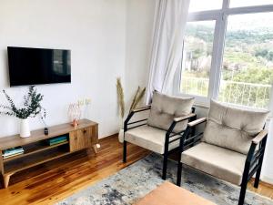 ein Wohnzimmer mit 2 Stühlen, einem Tisch und einem TV in der Unterkunft Cozy Mountain View House Near Olympos & Adrasan in Kumluca