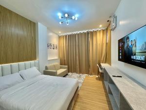 a bedroom with a large bed and a flat screen tv at Valencia Cozy Suites in Dumaguete
