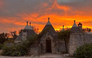 an old stone building with a sunset in the background at Trullo Amalia con piscina privata in Latiano
