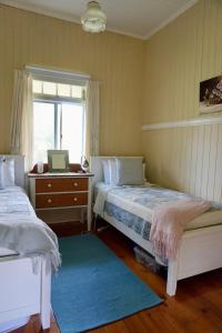 Un dormitorio con dos camas y un escritorio y una ventana. en Eighteen Mile Cottage, en Darlington