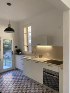 a kitchen with white cabinets and a sink and a window at L'oranger in Nyons