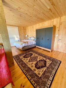a bedroom with a bed and a rug on a wooden floor at Casa de los pinos in Chacurra