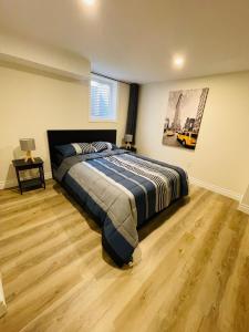 a bedroom with a large bed and a wooden floor at Modern Thorold Apt with Pool Table in Thorold