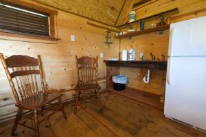 a kitchen with two wooden chairs and a refrigerator at Barn 2 Yellow Rose Canyon in Mount Enterprise