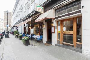 ロンドンにあるアパートメンツ クレイヴン テラスの市の通りにテーブルと椅子が並ぶレストラン