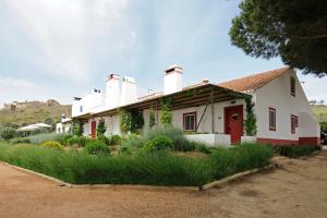 a white house with a red door and plants at Casas de Juromenha in Juromenha