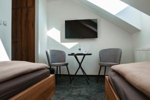 a bedroom with two beds and a table with two chairs at Pension Zwolenčan in Zvolen