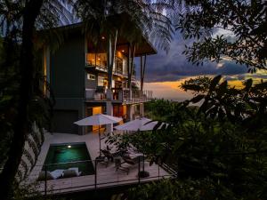 a building with chairs and umbrellas and a swimming pool at Villa Vista Del Mar - by Pura Villas in Dominical