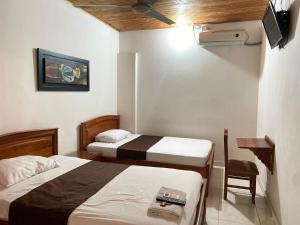 a hotel room with two beds and a tv at hotel kerana moon in Puerto Boyacá