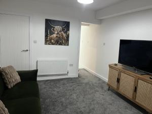 a living room with a couch and a flat screen tv at Fully Refurbished 3 Bed Terraced House with Ensuite Central Rugby in Rugby