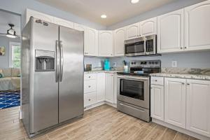 una cucina con mobili bianchi e un frigorifero in acciaio inossidabile di Aminas Cottage 3 Bedroom Home a Kill Devil Hills