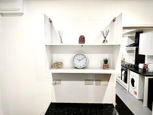 una cocina blanca con reloj en un estante en Leicester Haven near Train Station, en Leicester