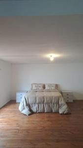 a bed in a white bedroom with a wooden floor at Loft García in Mendoza