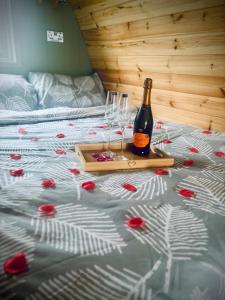 a bottle of wine and two wine glasses on a bed at Knockmany View Glamping in Augher