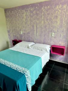 a bedroom with a bed and a purple wall at Casa Tô na Onda in Prado